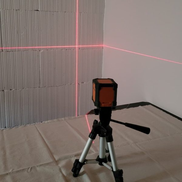 image d'un niveau laser sur trépied qui trace le niveau sur deux murs