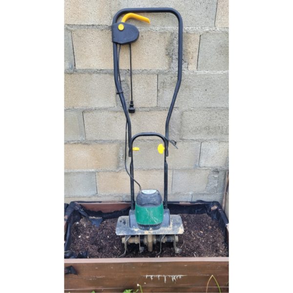 motobineuse dans un jardin accolée à un mur